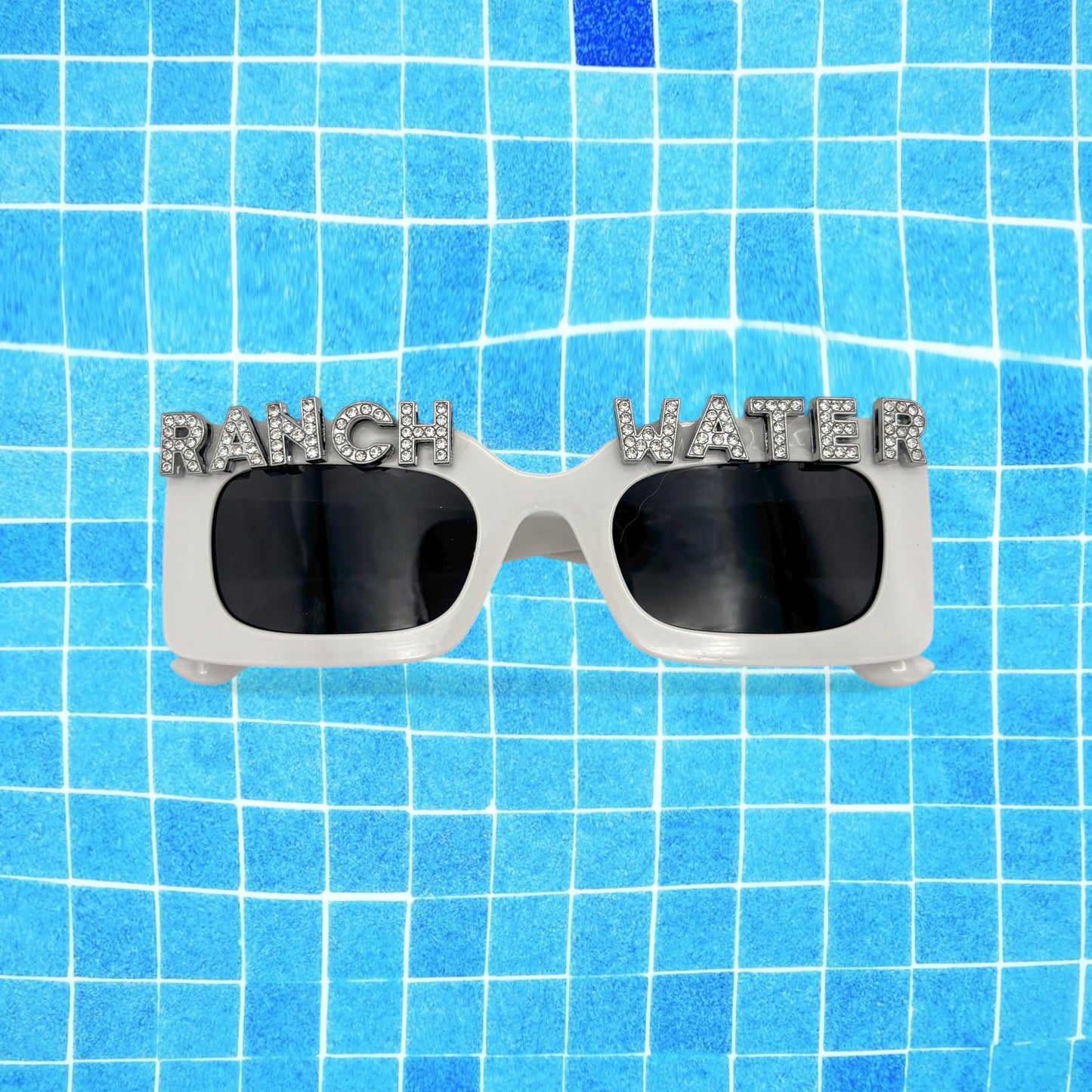 Sunglasses with 'RANCH WATER' text on a blue tiled background