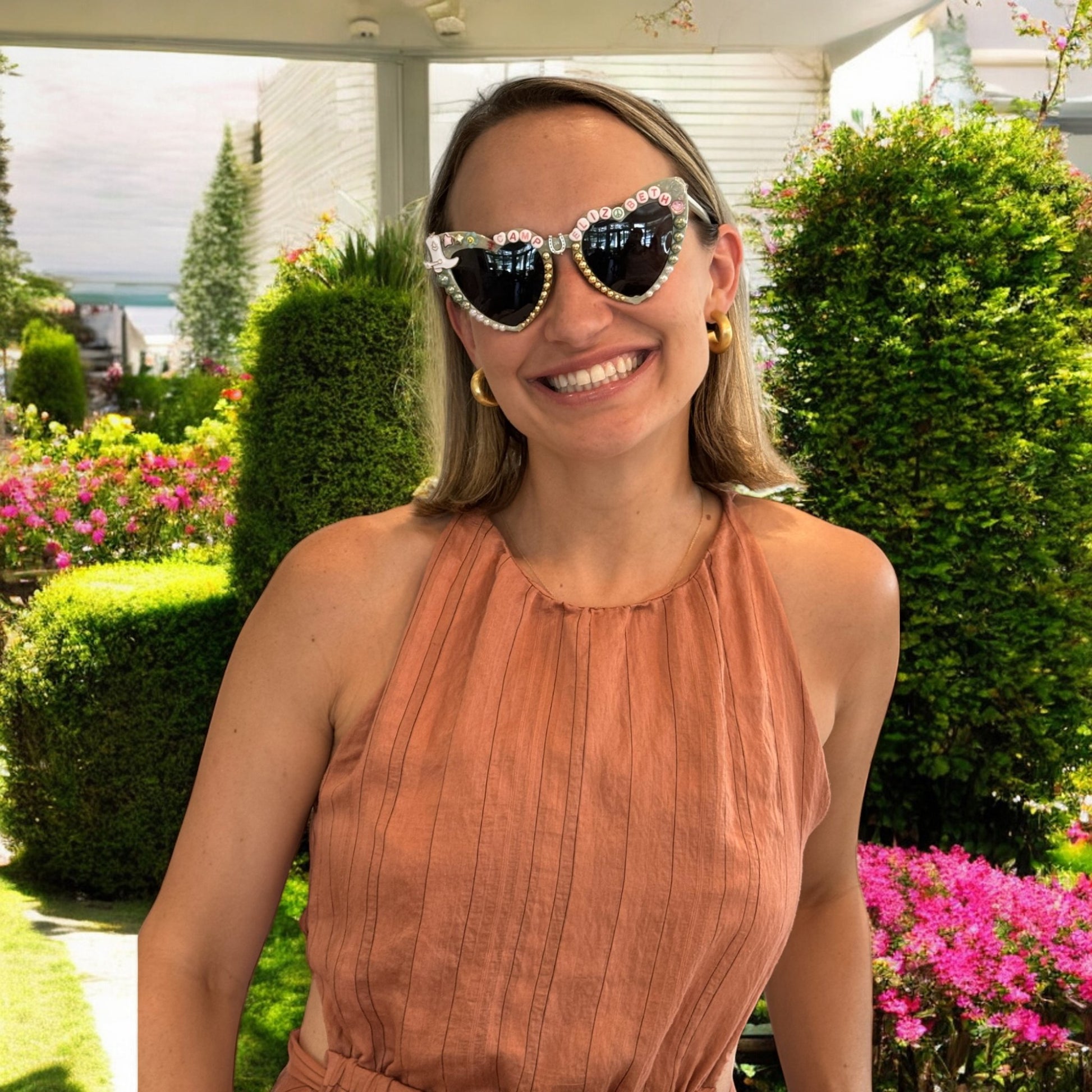 A young woman wearing heart sunglasses that say Camp Bach