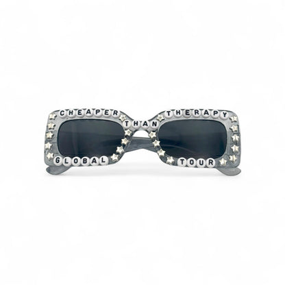 Gray concert sunglasses with “Cheaper Than Therapy” text
